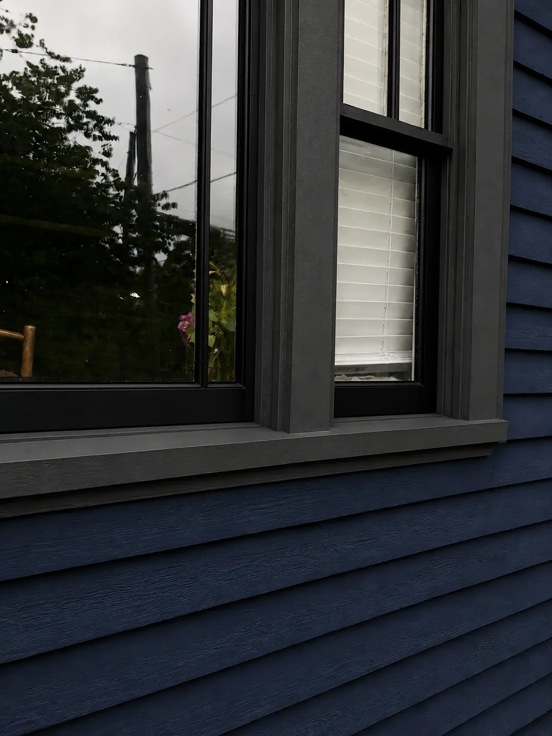 Restored window trim and deep blue siding after painting.
