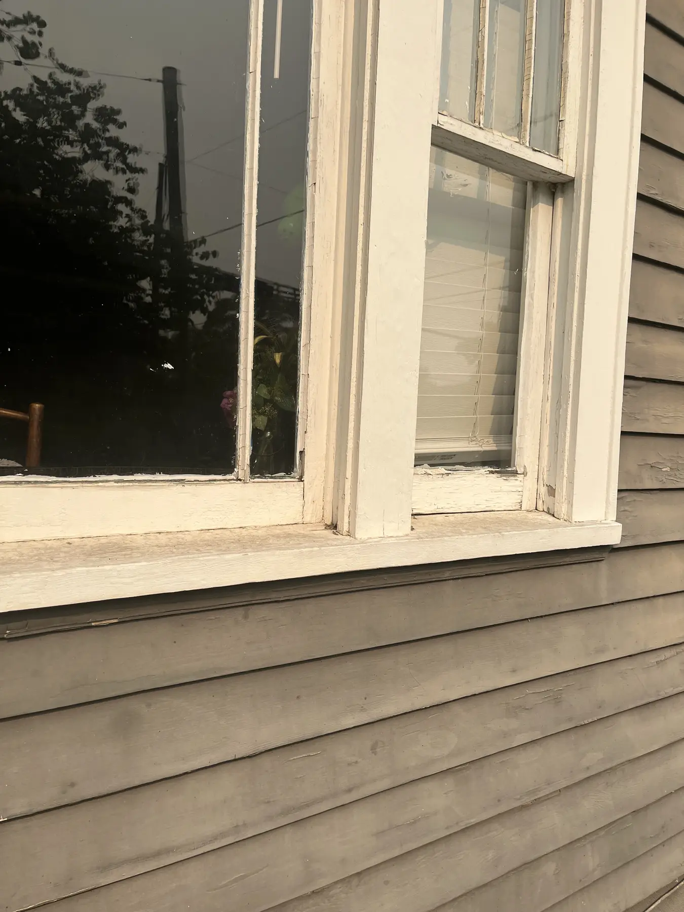 Worn white window trim and weathered siding before preparation.