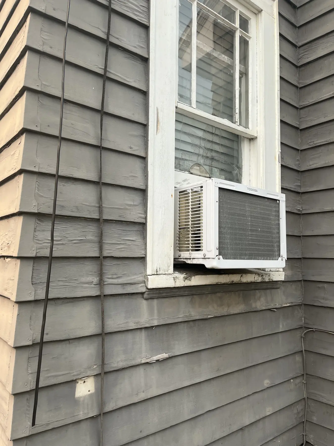 Weathered siding and window assembly before restoration.