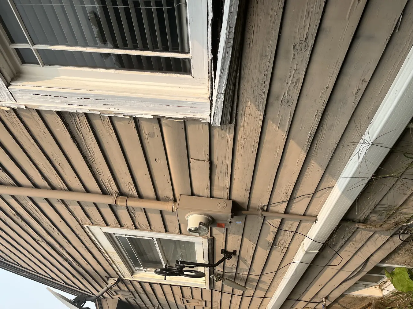 Aged exterior siding and trim at a utility penetration before preparation.